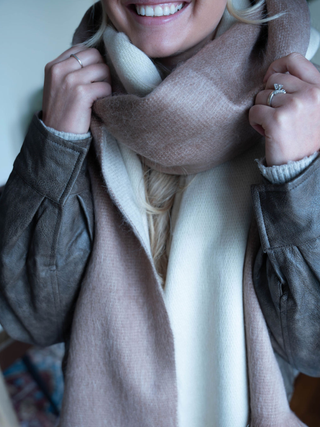 Person wearing a brown coat and beige scarf with a blurred background