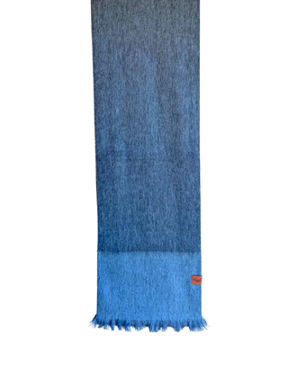 A blue gradient knit scarf with fringe, hanging from a yellow wooden hanger against a plain white background.
