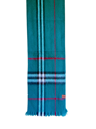 A teal green plaid scarf with light blue, white, and red stripes, hanging from a wooden hanger against a white background.
