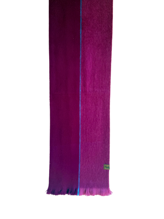 A long woven scarf in deep magenta and purple tones, hanging from a wooden hanger against a plain white background.