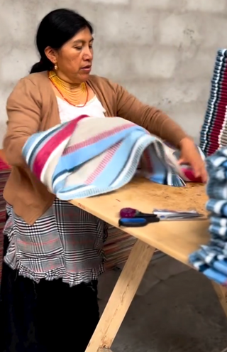 Maker in Ecuador working withalpaca scarf at a table in a workshop setting